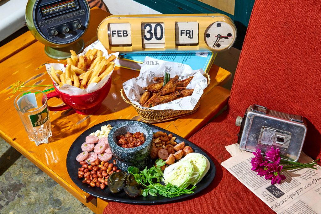 Fried chicken, fries and a Thai snack platter on a vintage table at TUBA Bangkok