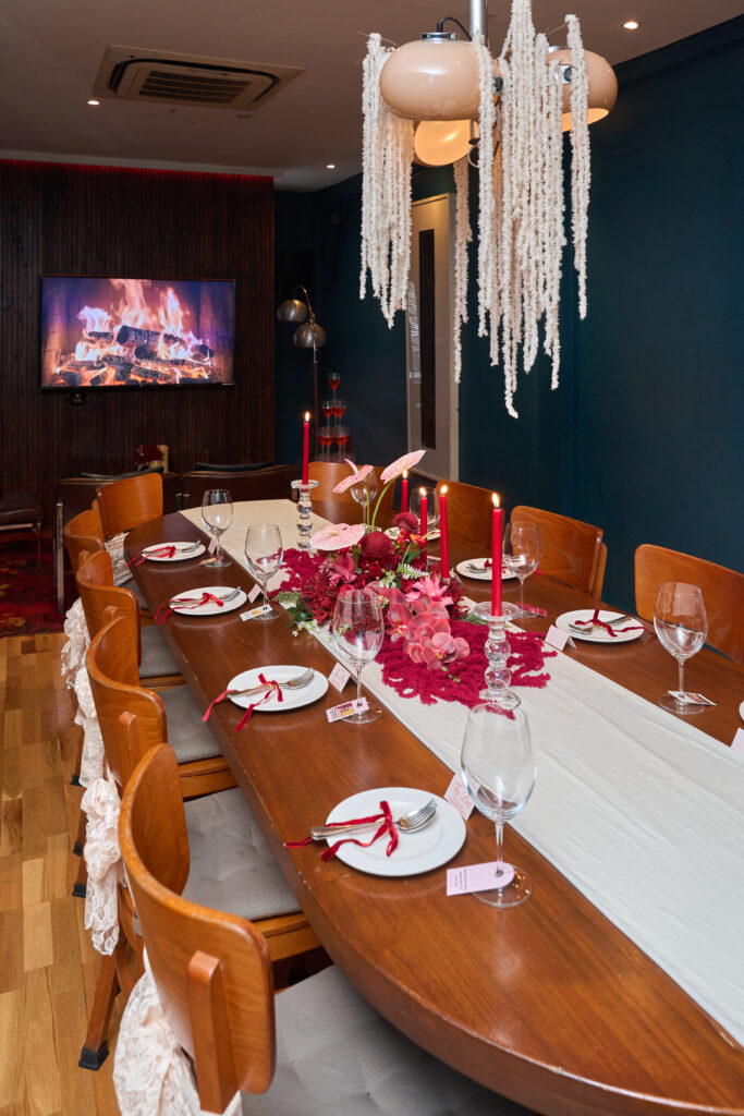 The Gallery Room at TUBA Bangkok decorated for a private party - red flowers and candles down the table, name cards at each seat and a hanging floral installation