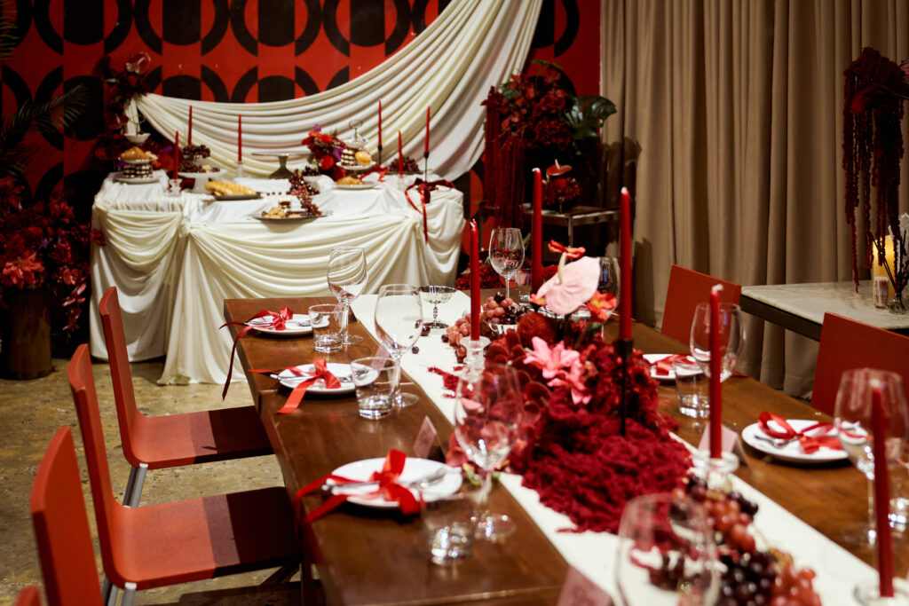 The Museum Room at TUBA Bangkok dressed for a private party with a red flower runner, tall candles and a draped dessert table