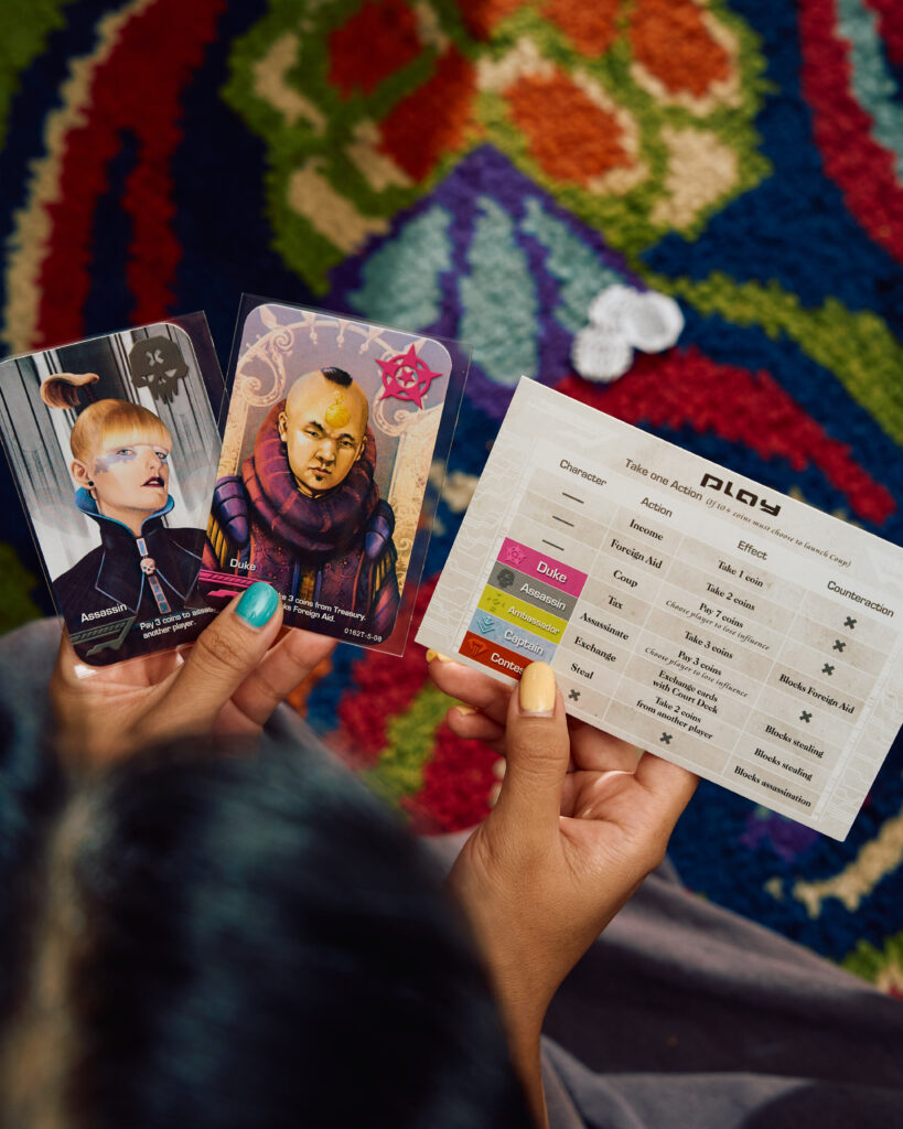 A guest holding Coup cards above the patterned vintage carpet in a TUBA private room