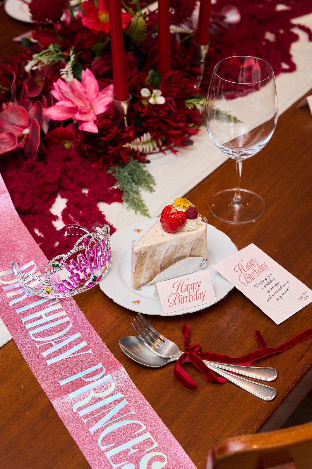 Birthday cake slice, tiara, sash and greeting card on a decorated table in a TUBA private room