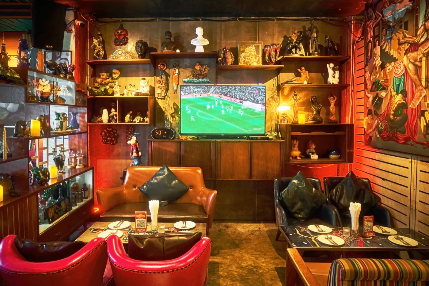 Red leather booth at TUBA Bangkok set for dinner beside shelves of collectibles