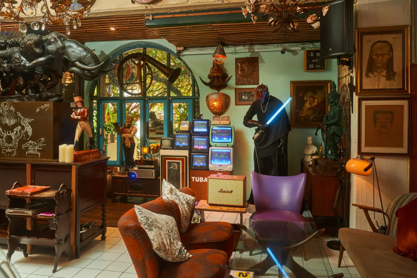 Wide view of the vintage lounge at TUBA Bangkok with arcade machines, collectible figures and a leather sofa